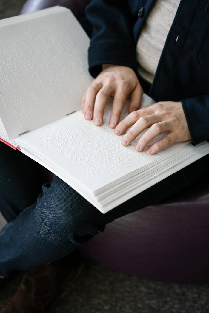 Hands reading a braille book, highlighting tactile literacy and accessibility.